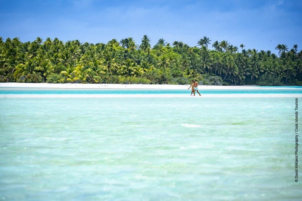 Paar beim Spaziergang in der türkisblauen Lagune von Aitutaki auf den Cook Inseln