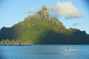 Kanufahrer in der Lagune von Bora Bora mit Blick auf Mount Otematu und Overwater Bungalows.