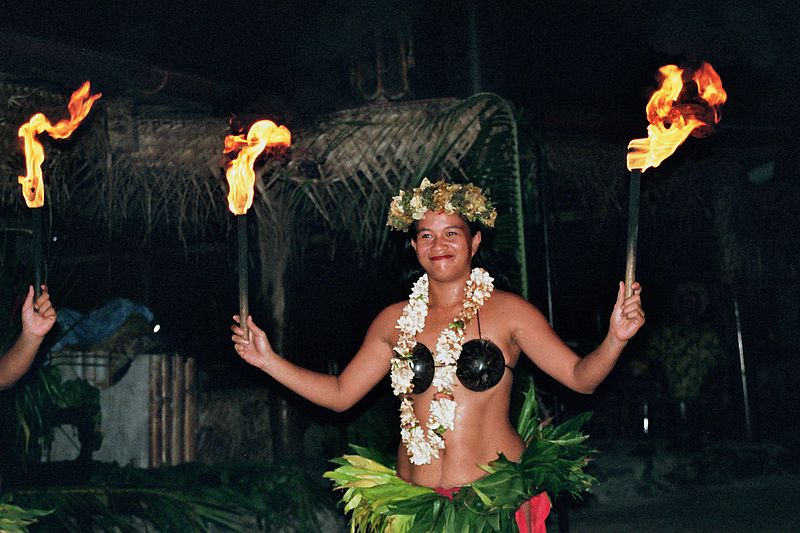 Polynesische Tänzerin auf Moorea im Tiki Village mit Kokusnussbikini, Blumenkranz im Haar und brennenden Fackeln in der Hand.
