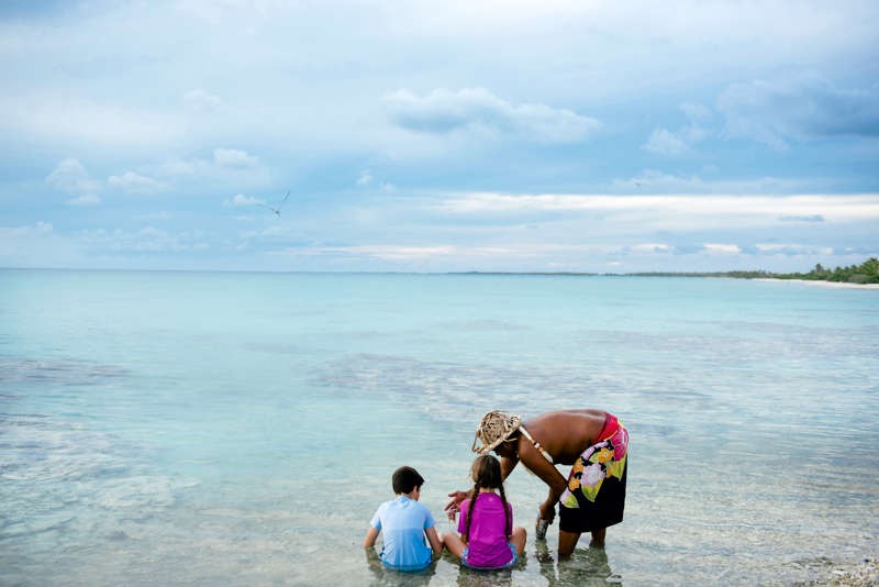 Insulaner zeigt zwei Kindern die Fische in der Lagune von Rangiroa in Französisch Polynesien.