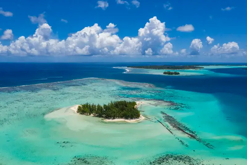 Einsame vorgelagerte Insel in der Südsee umgeben von weißem Sandstrand und türkisblauem Meer.
