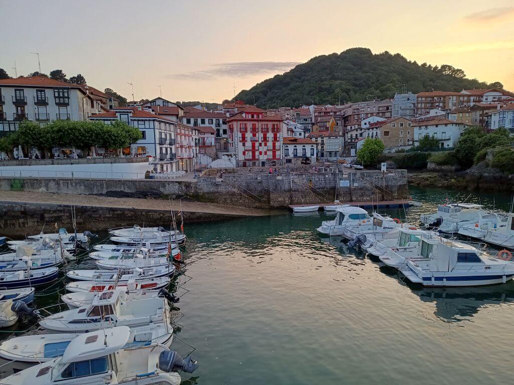 Der Hafen von Mundaka bei Sonnenuntergang mit bunten Häusern im Hintergrund