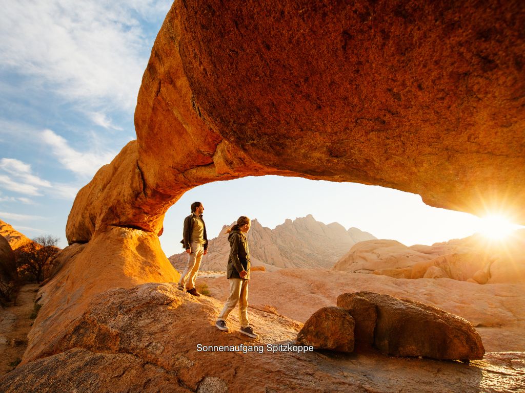 Vater und Tochter in der Spitzkoppe Region unter einem Felsen bei Sonnenaufgang