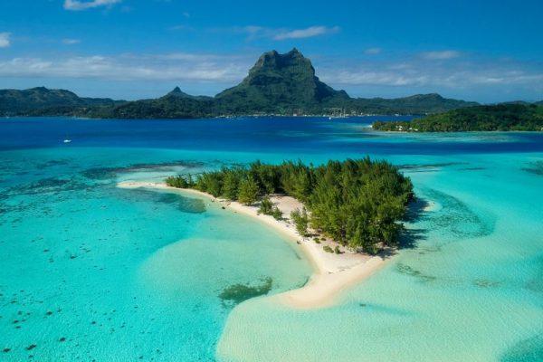 Blick auf die Südseeinsel Bora Bora in Französisch Polynesien mit einem vorgelagerten Motu und türkisfarbener Lagune.