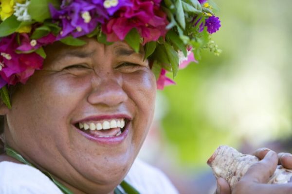 Lachende polynesische Frau mit Blumenkranz beim Inselhopping Polynesien